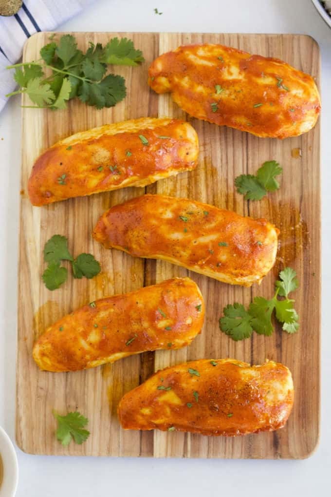 The cooked chicken on a wooden cutting board.
