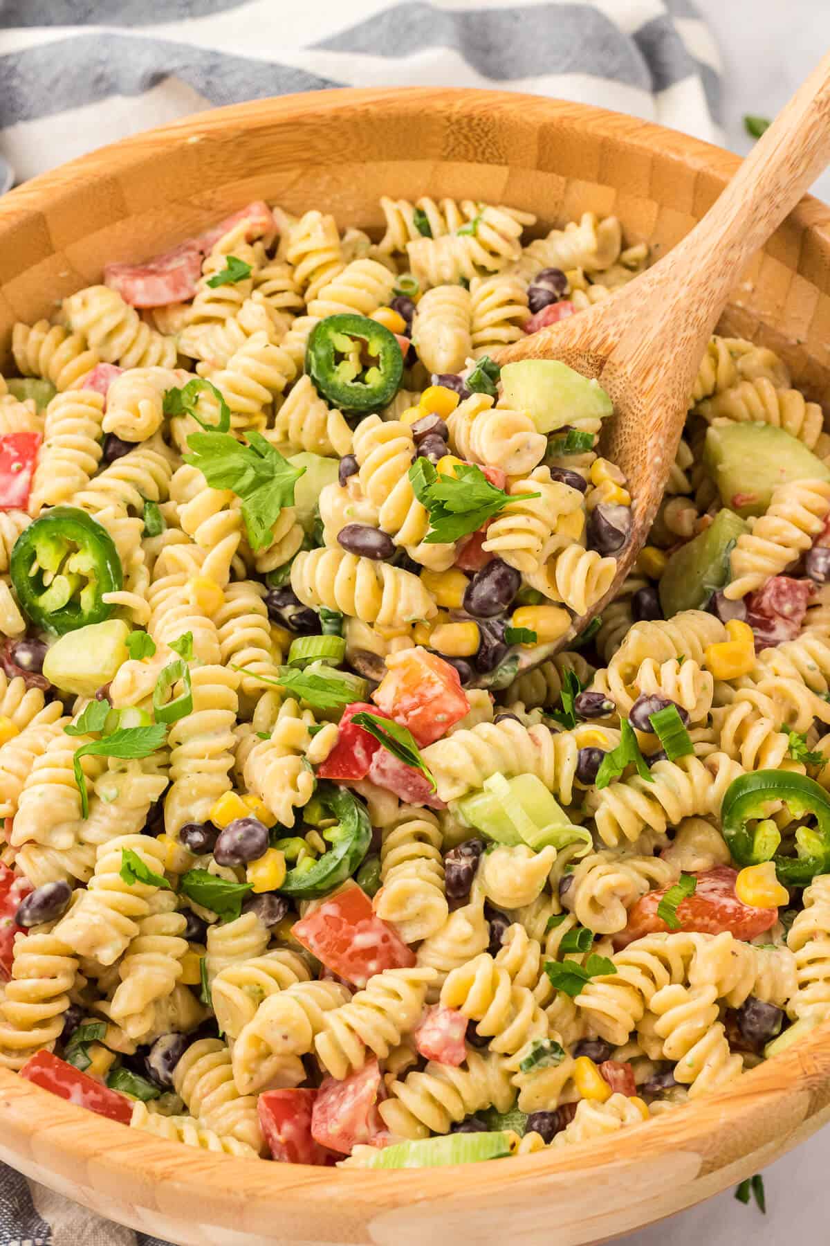 A bowl of jalapeno ranch pasta salad with a wooden spoon.