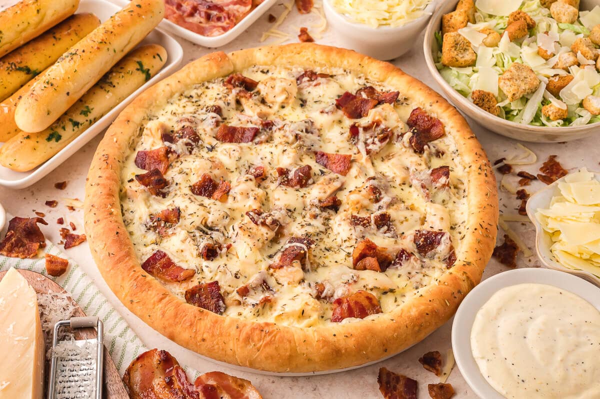 A pizza surrounded by ingredients.