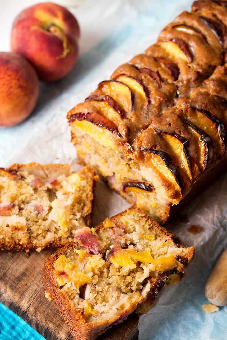 Peach bread on a wooden cutting board with slices off the end.