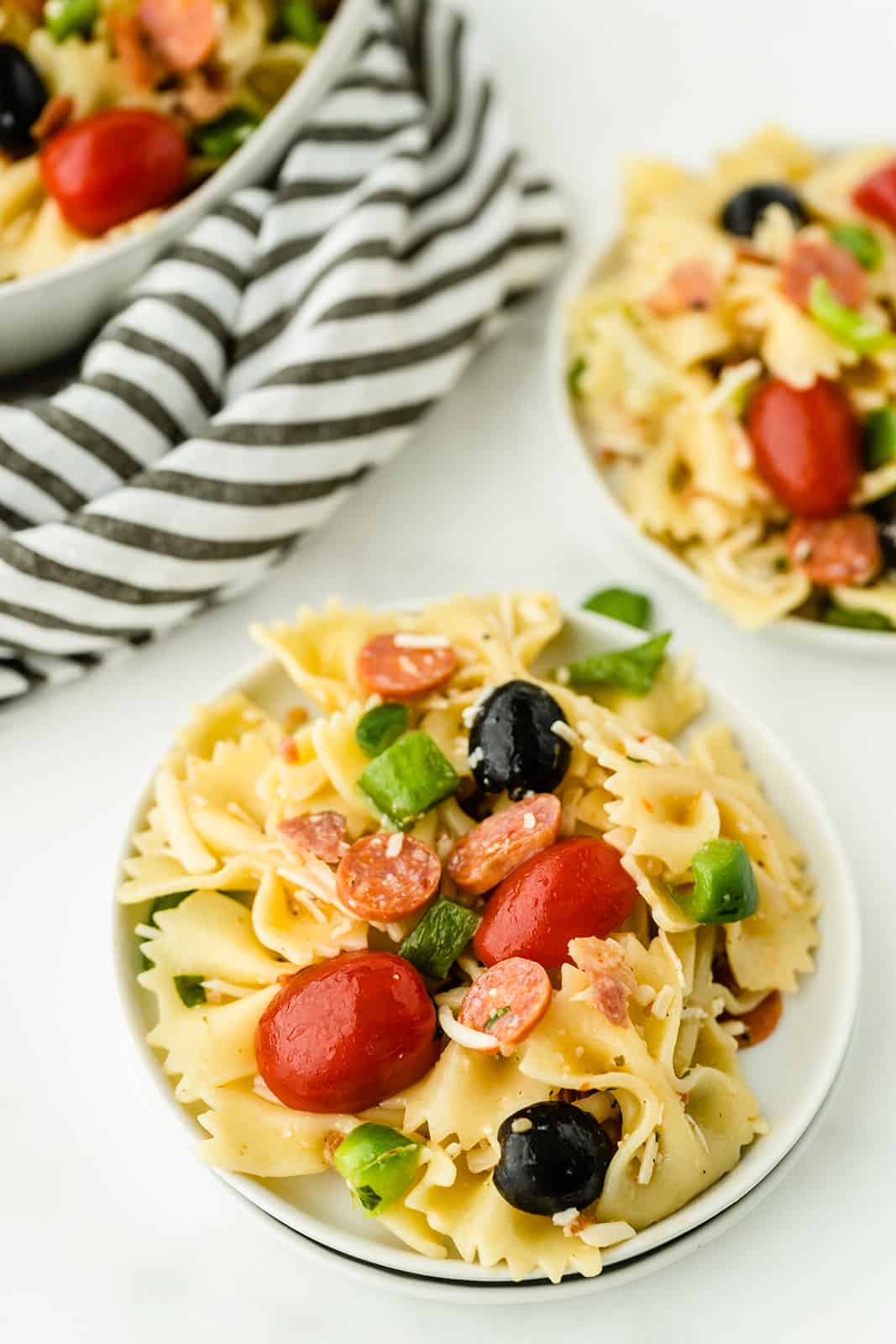 Pizza Pasta Salad - A perfect summer dish with all the best pizza flavors! Salty pepperoni and olives are coated in tangy Italian dressing and covered in cheese.