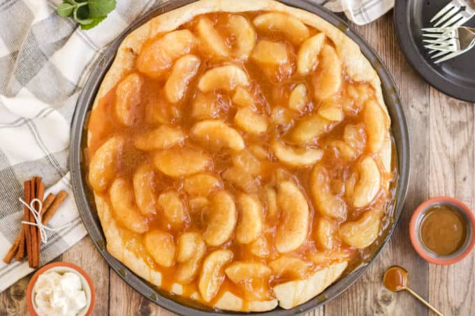 Caramel Apple Pizza - The PERFECT fall dessert pizza! Sweet cinnamon apple pie filling with rich caramel covering a basic pizza crust for the taste of pie without the mess and wait.