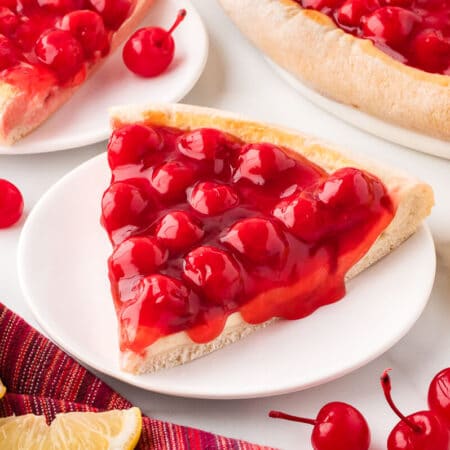 A slice of cherry cheesecake pizza on a plate.