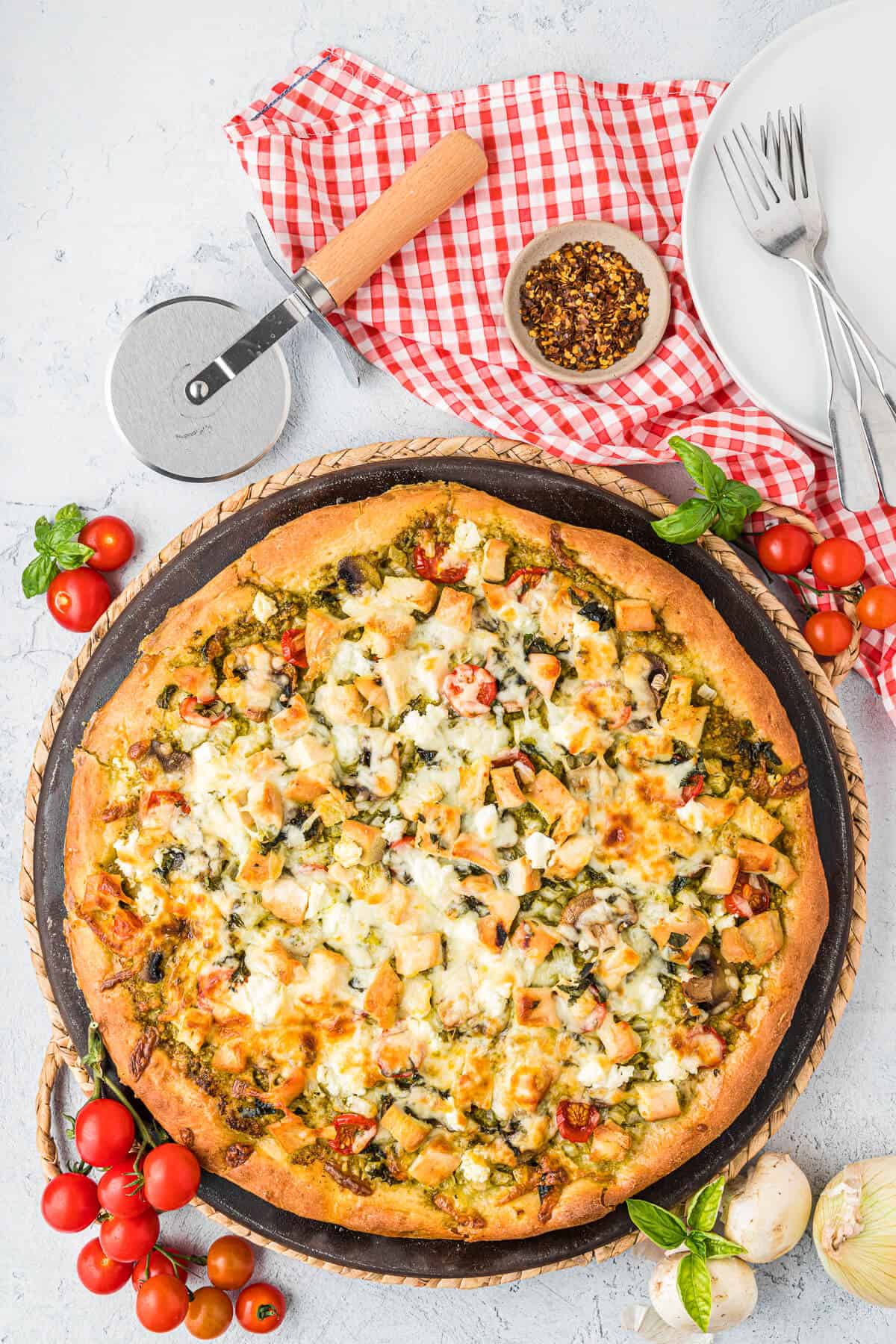 A chicken pesto pizza on a pizza pan.