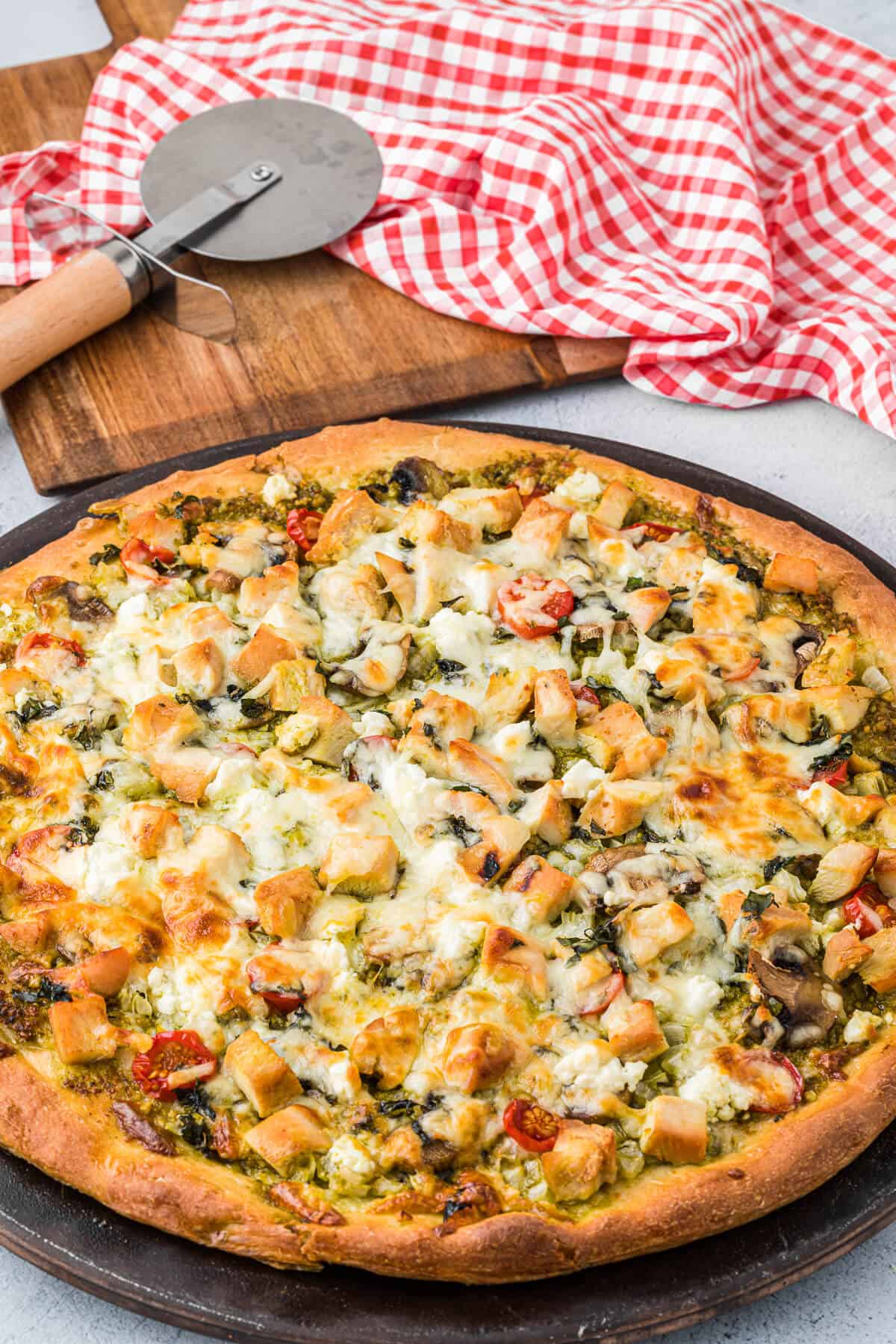 Chicken pesto pizza on a pizza pan.