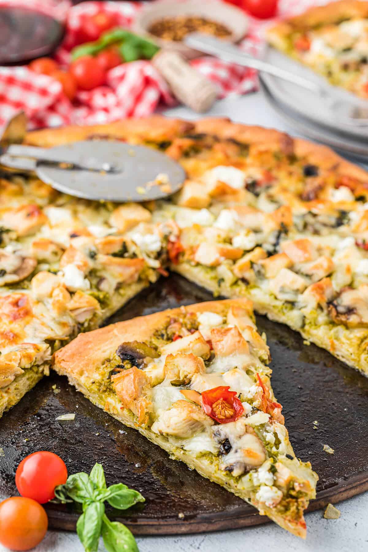 Slices of chicken pesto pizza on a pizza pan.