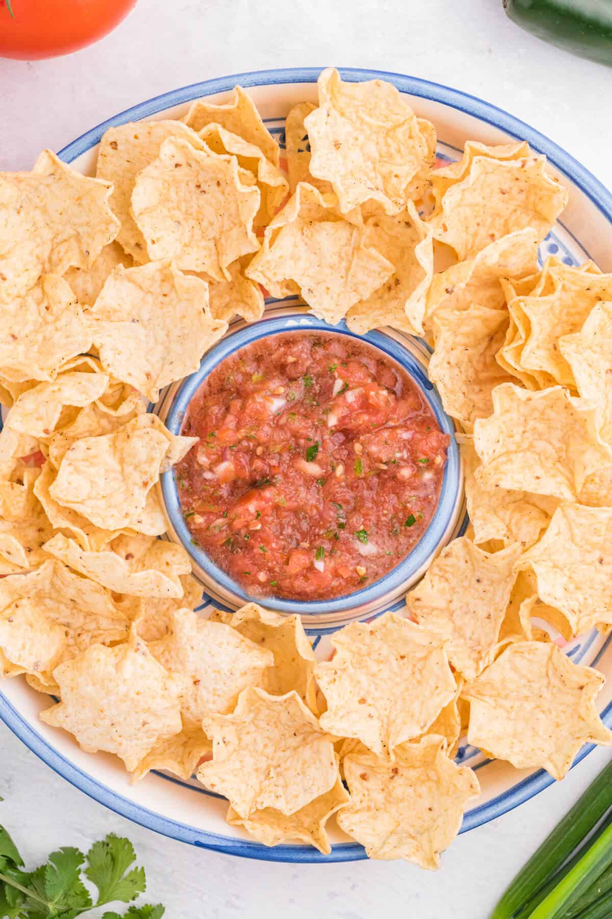 Garden salsa on a serving tray surrounded by tortilla chips.