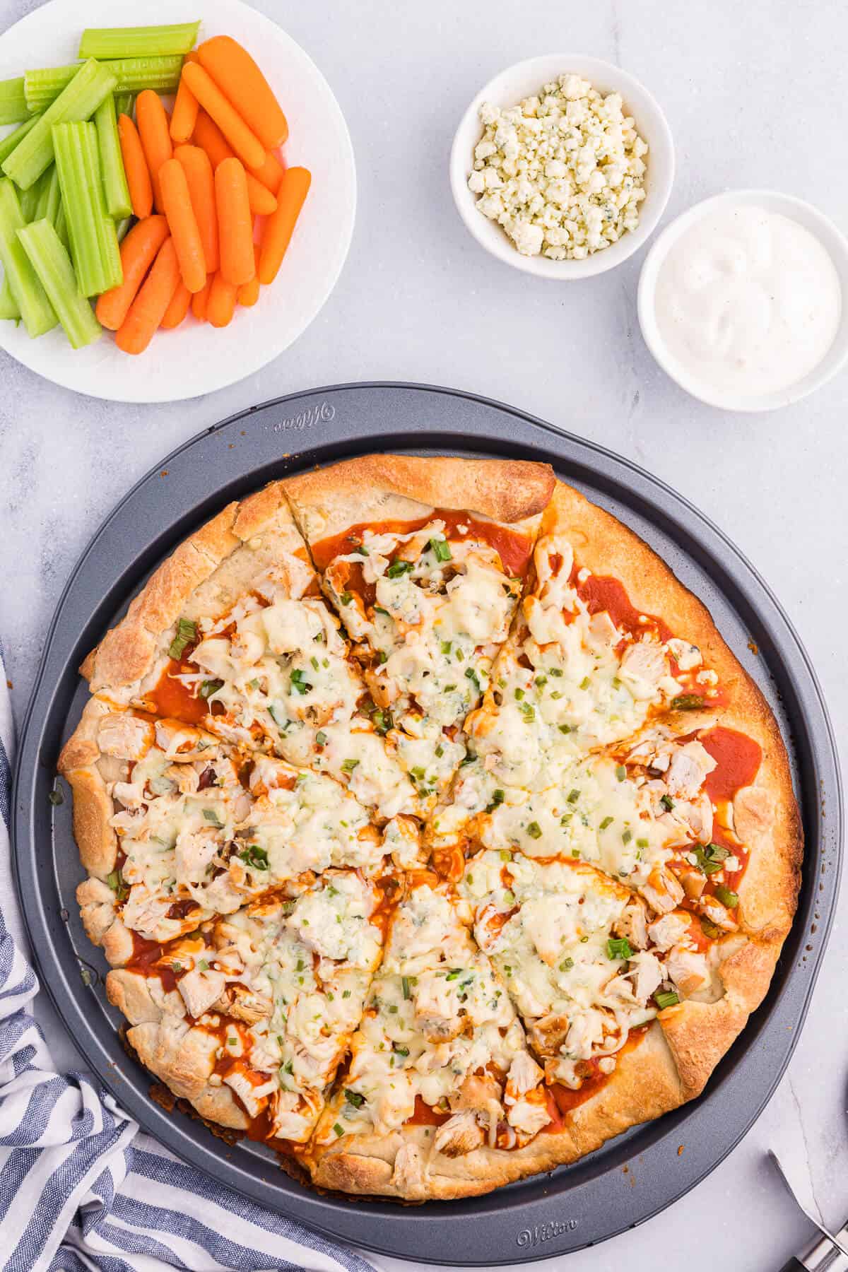 Buffalo chicken pizza on a pizza baking sheet.