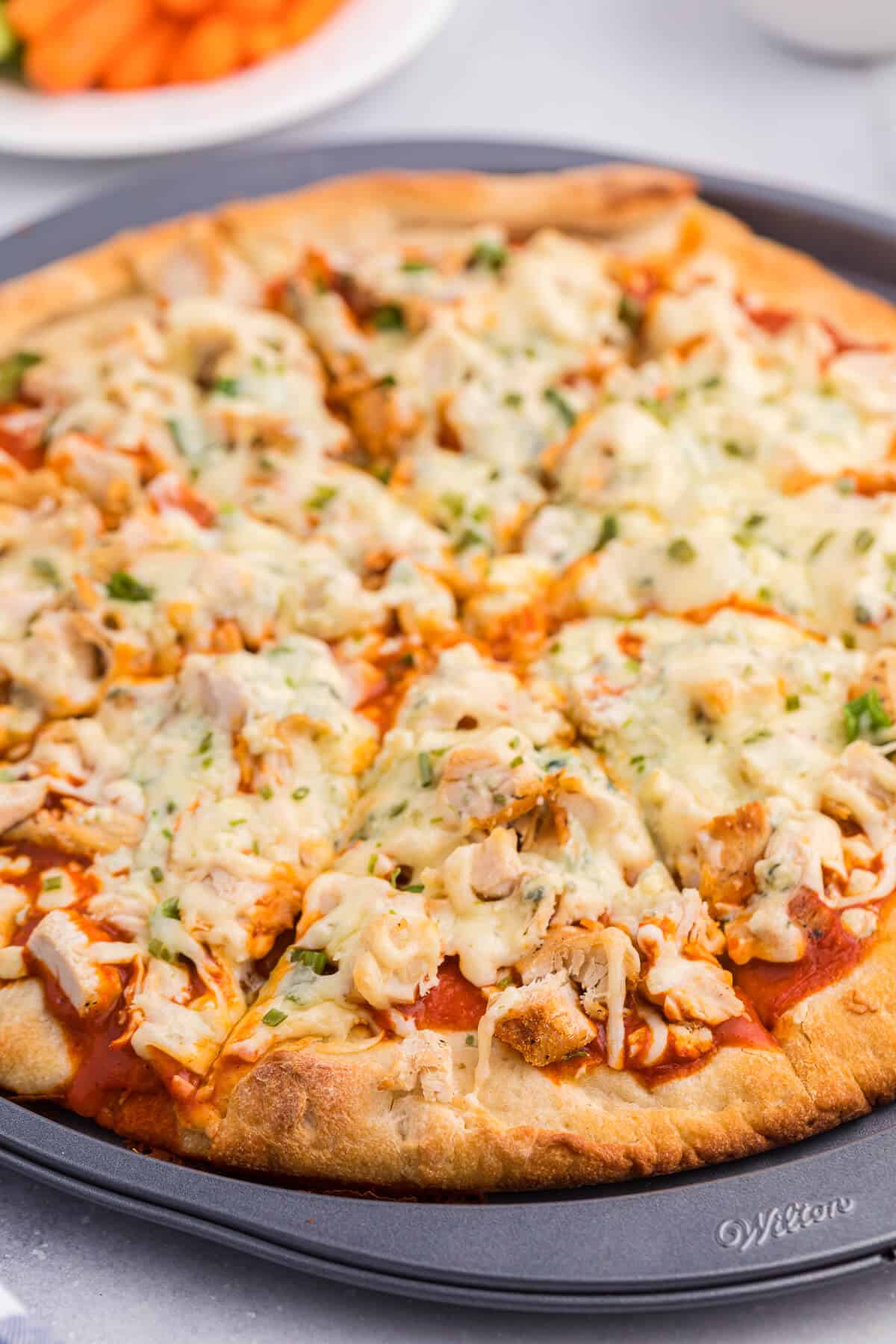 Buffalo chicken pizza on a pizza baking sheet.