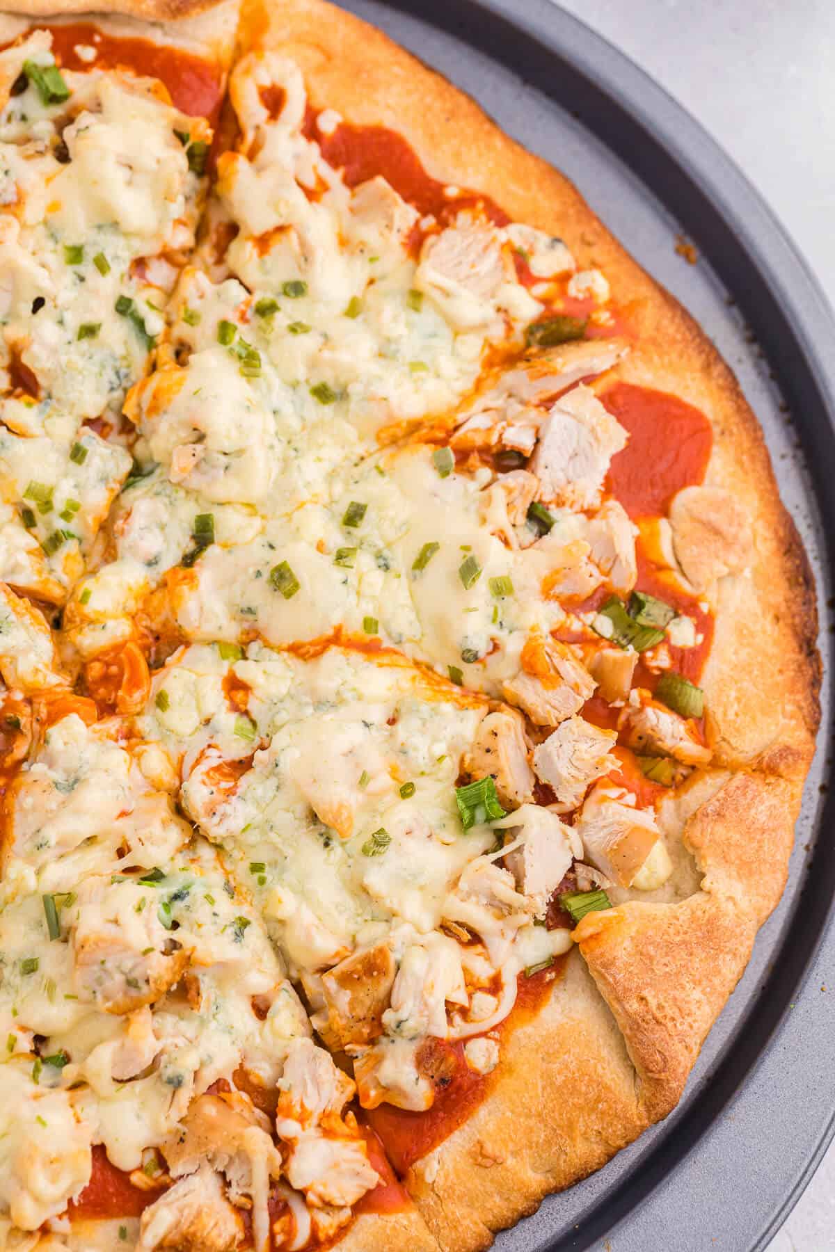 Buffalo chicken pizza on a pizza baking sheet.