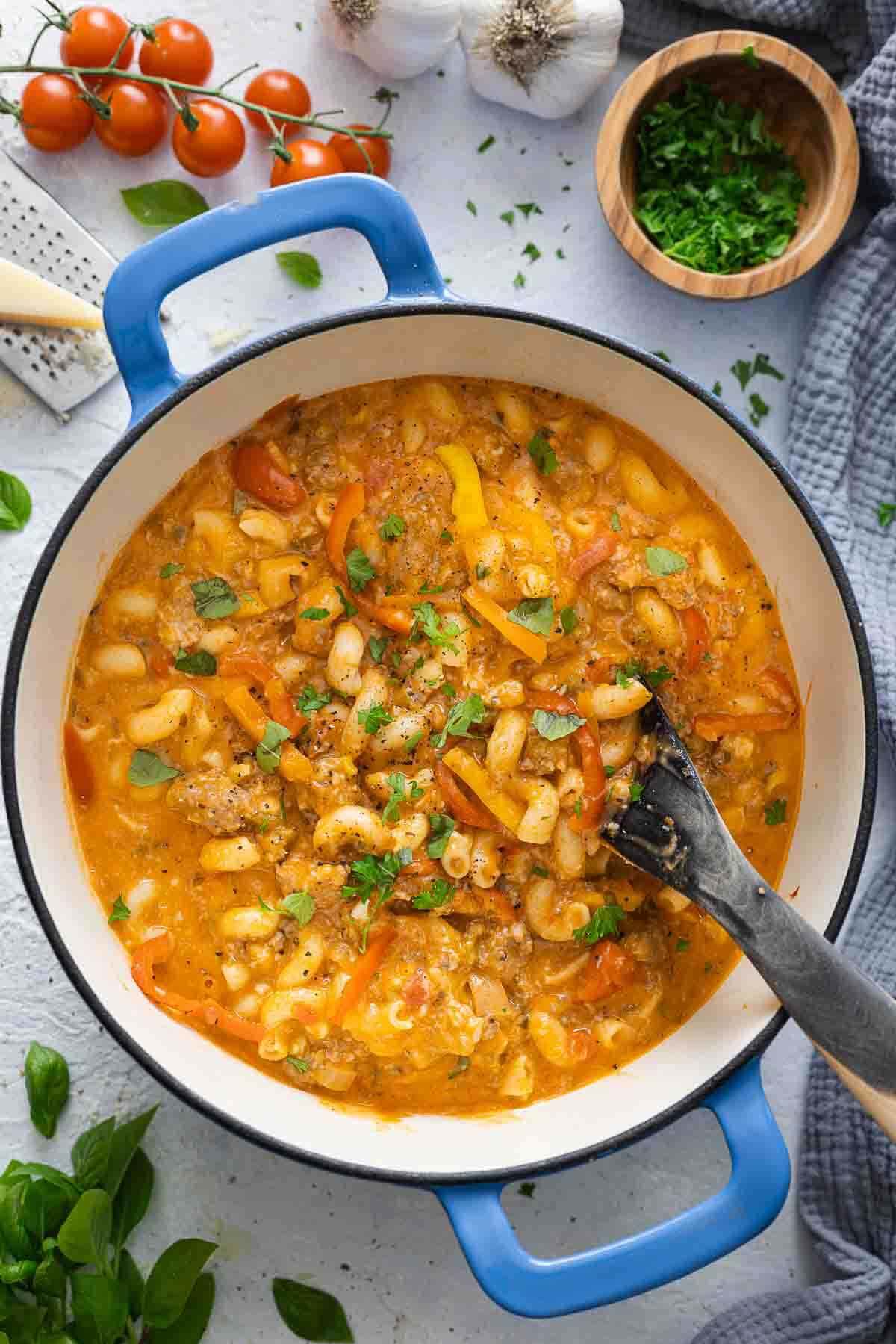 Spicy sausage and pepper pasta in a pot with a spoon.