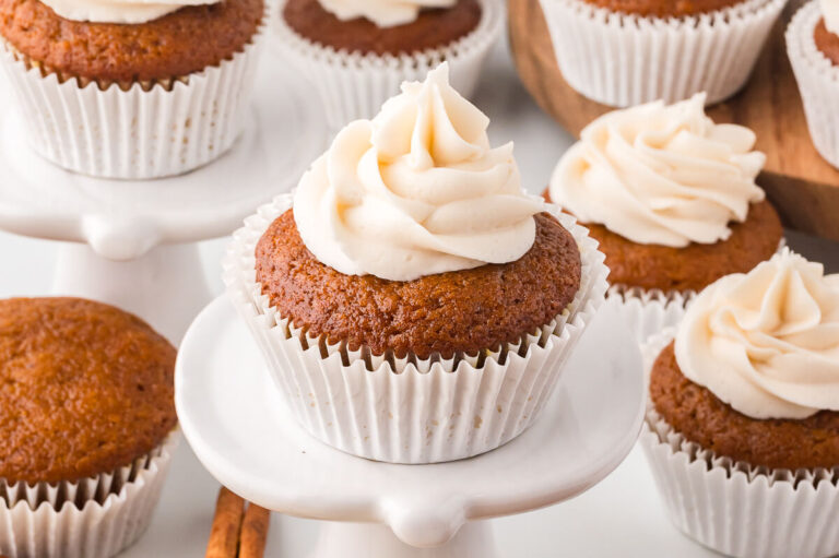 A cupcake on a stand with a group of cupcakes in the background.