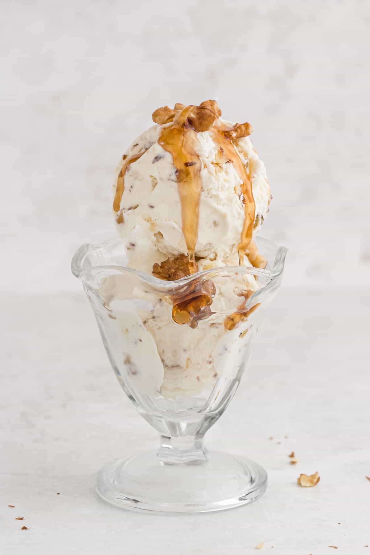 Maple walnut ice cream in a parfait dish with maple syrup on top.
