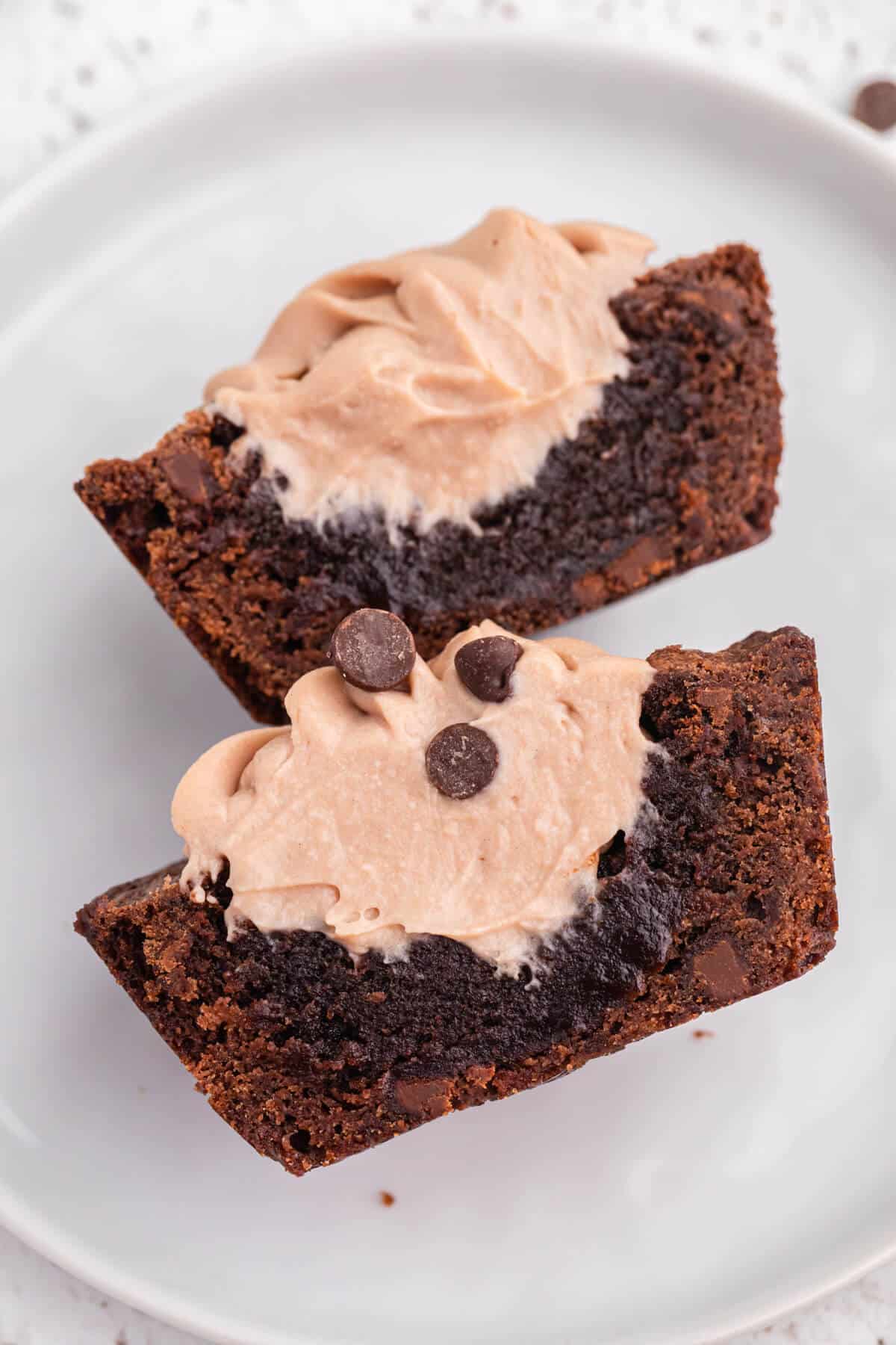 A brownie cheesecake cup cut in half on a plate.