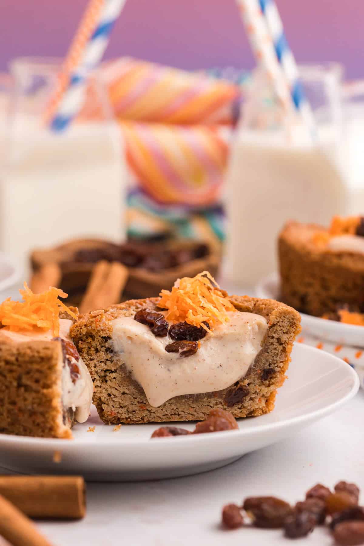 A carrot cake cup cut in half on a plate.