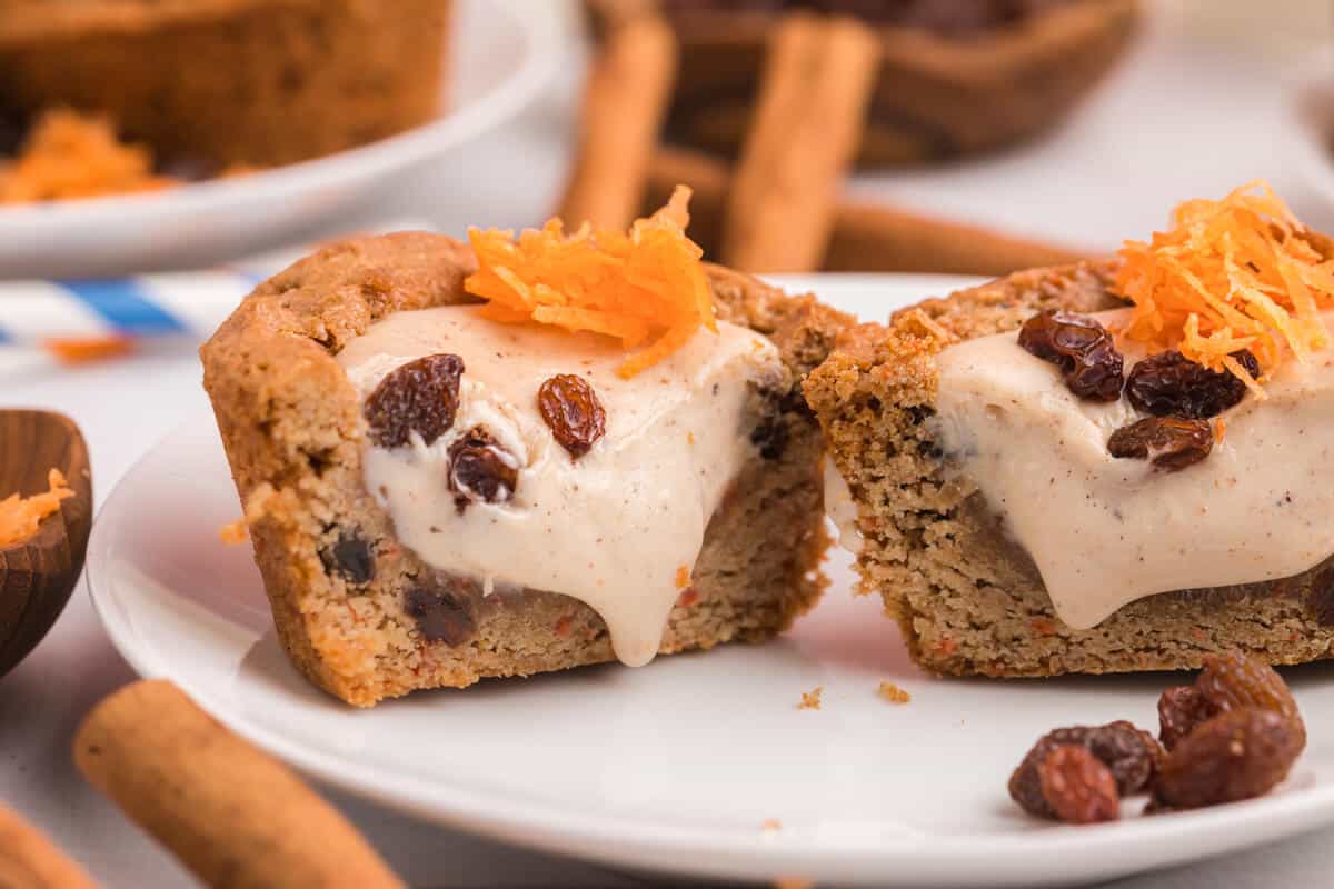 A carrot cake cup cut in half on a plate.