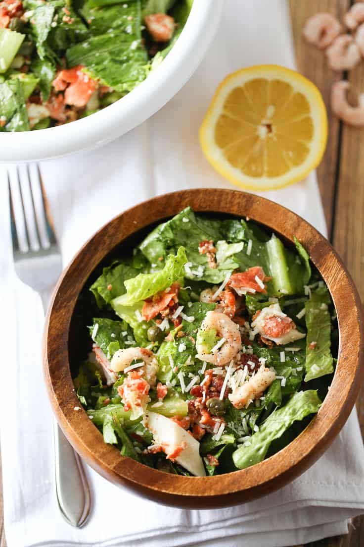 Seafood Caesar Salad Recipe - Elevate your regular dinner salad tonight! Salmon, shrimp, and crab meat are delectable in homemade Caesar dressing and topped with capers and bacon.