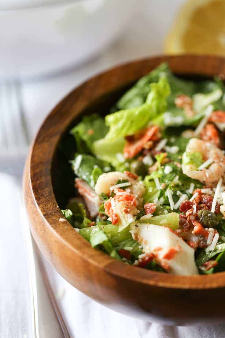 Seafood Caesar Salad Recipe - Elevate your regular dinner salad tonight! Salmon, shrimp, and crab meat are delectable in homemade Caesar dressing and topped with capers and bacon.