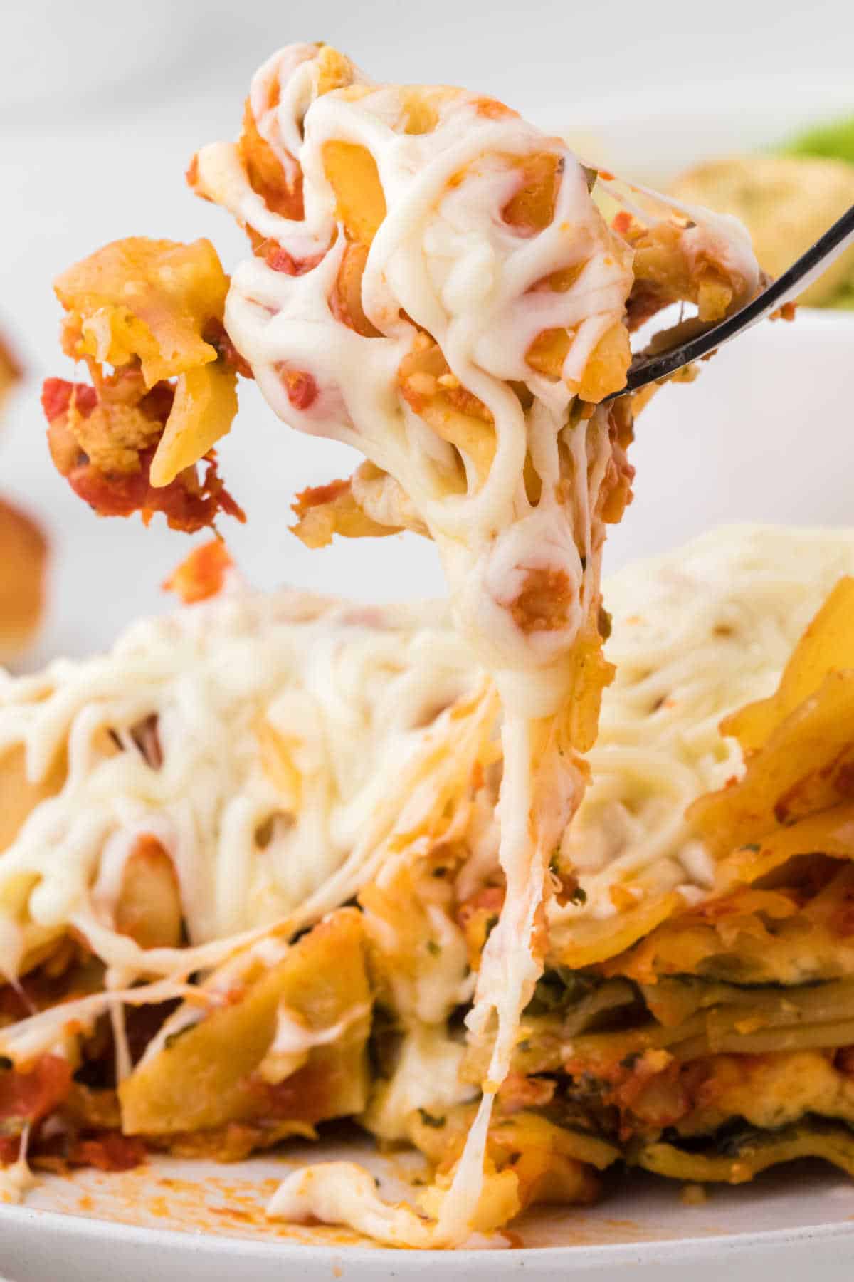 A fork lifting up a piece of lasagna with lots of cheese.