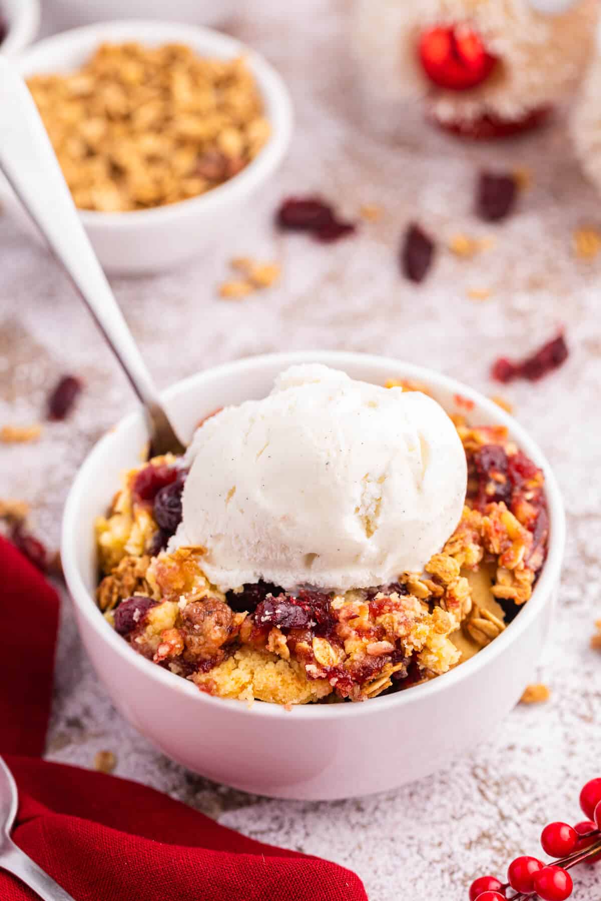 Cranberry cobbler dump cake with vanilla ice cream on top in a bowl.