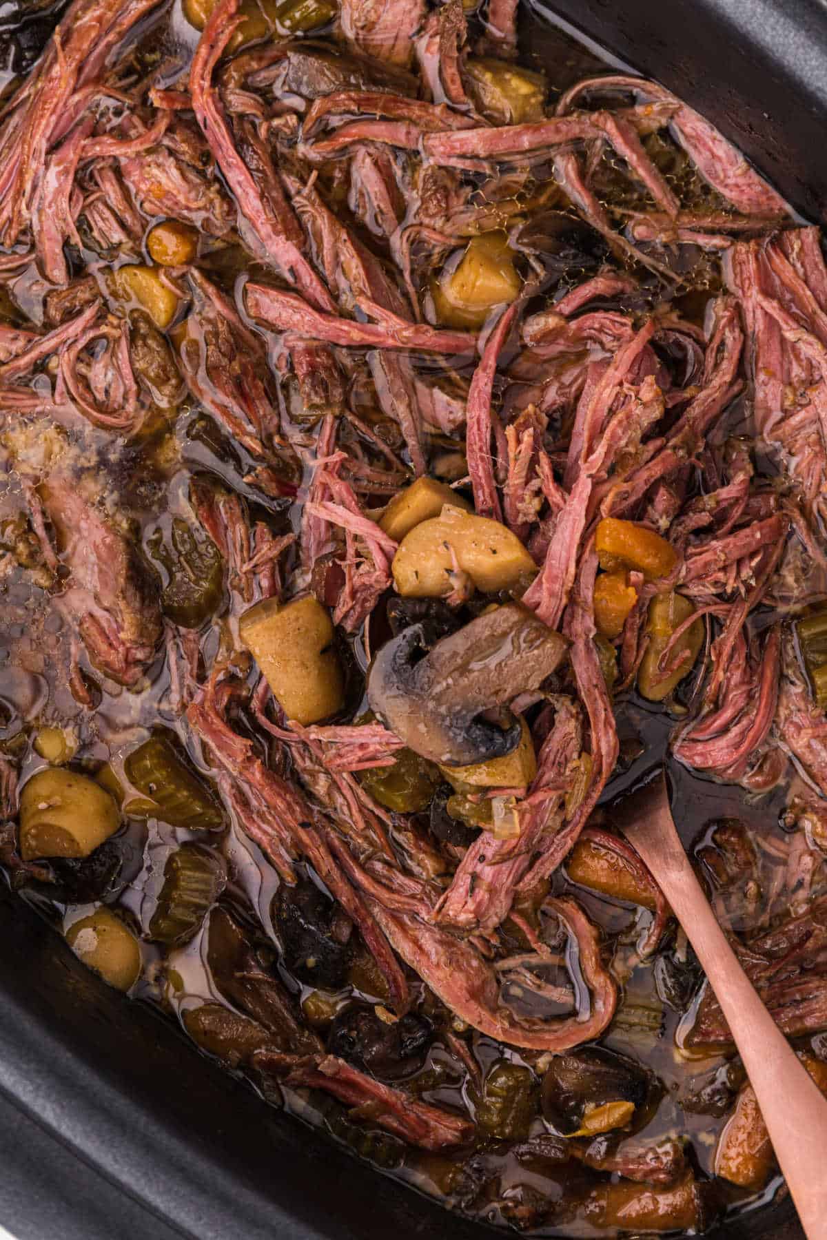 Beef brisket soup in a crockpot with a serving spoon.