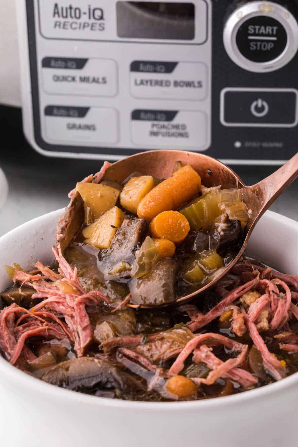 A ladle serving beef brisket soup into a bowl.