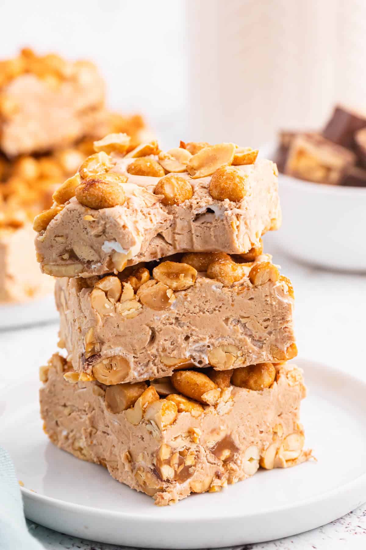 A stack of nougat bars on a plate with a bite out of the top bar.