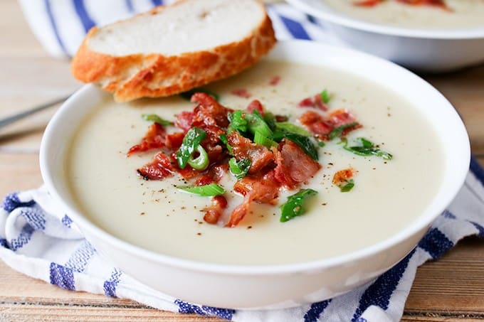 Cauliflower soup in a bowl with a slice of bread.