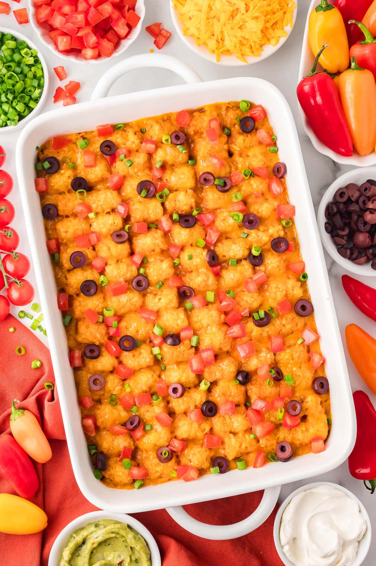 A pan of Mexican Tater Tot Casserole surrounded by ingredients.