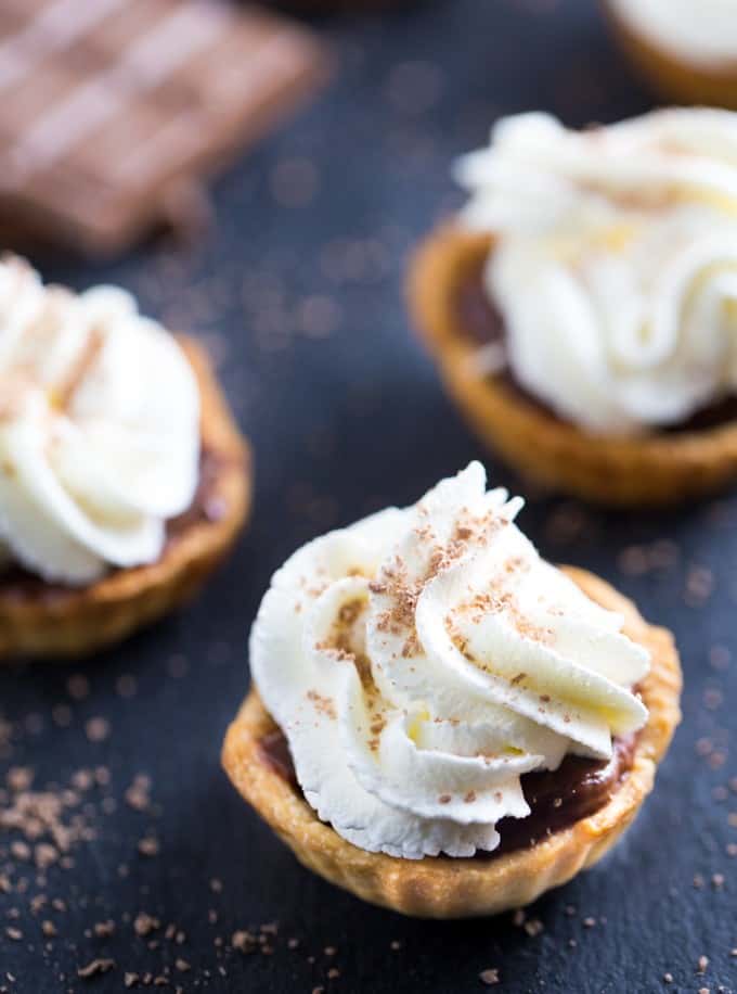 Chocolate Cream Tarts - Bite sized tarts filled with a smooth, rich chocolate filling and topped with sweet whipped cream. I can never stop at just one!