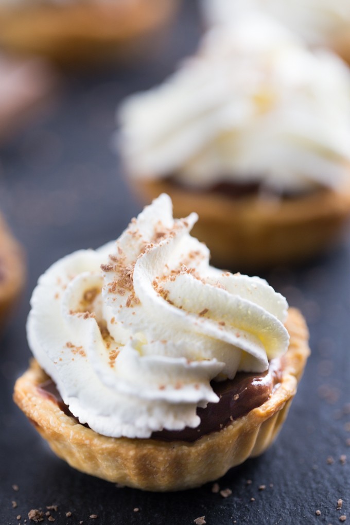Chocolate Cream Tarts - Bite sized tarts filled with a smooth, rich chocolate filling and topped with sweet whipped cream. I can never stop at just one!