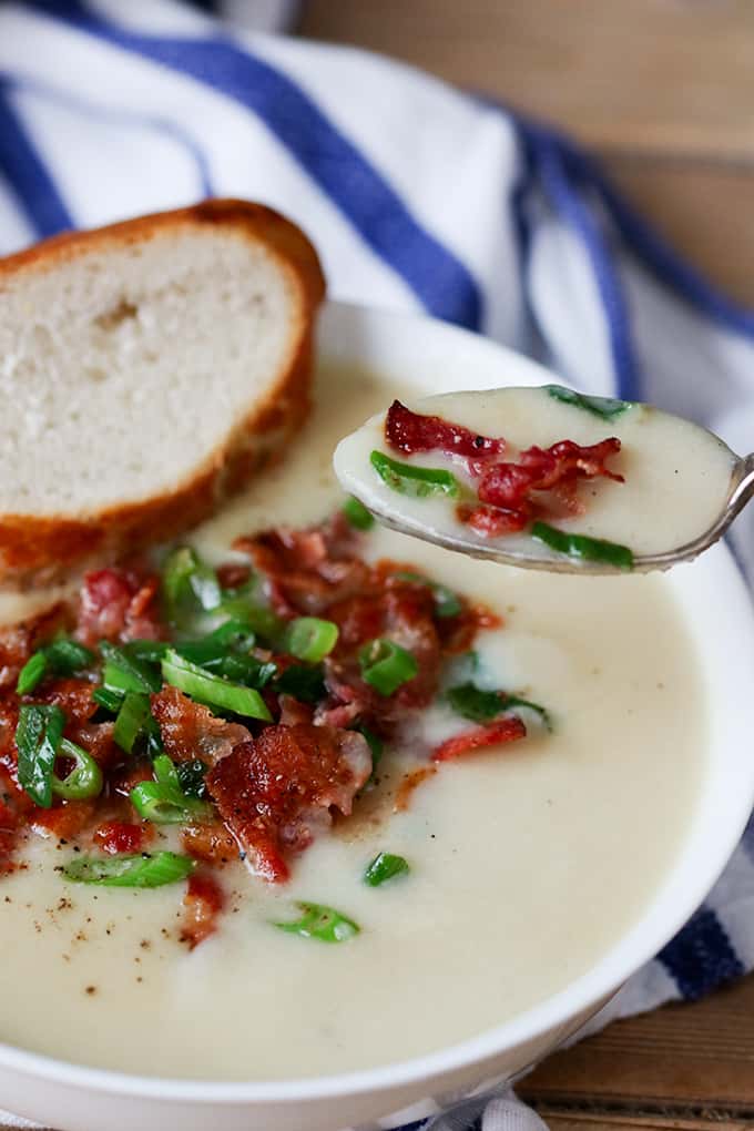 Cauliflower soup with bacon on a spoon.