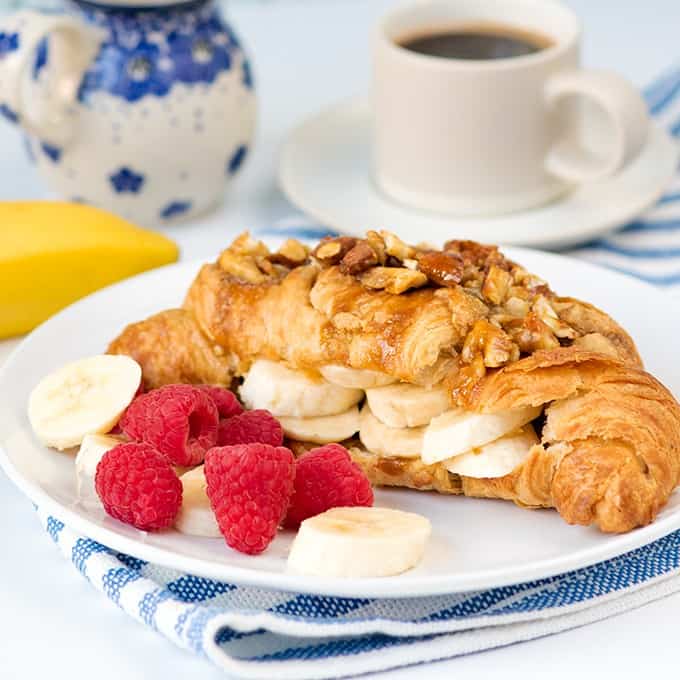 Sticky banana croissant on a plate with fruit.