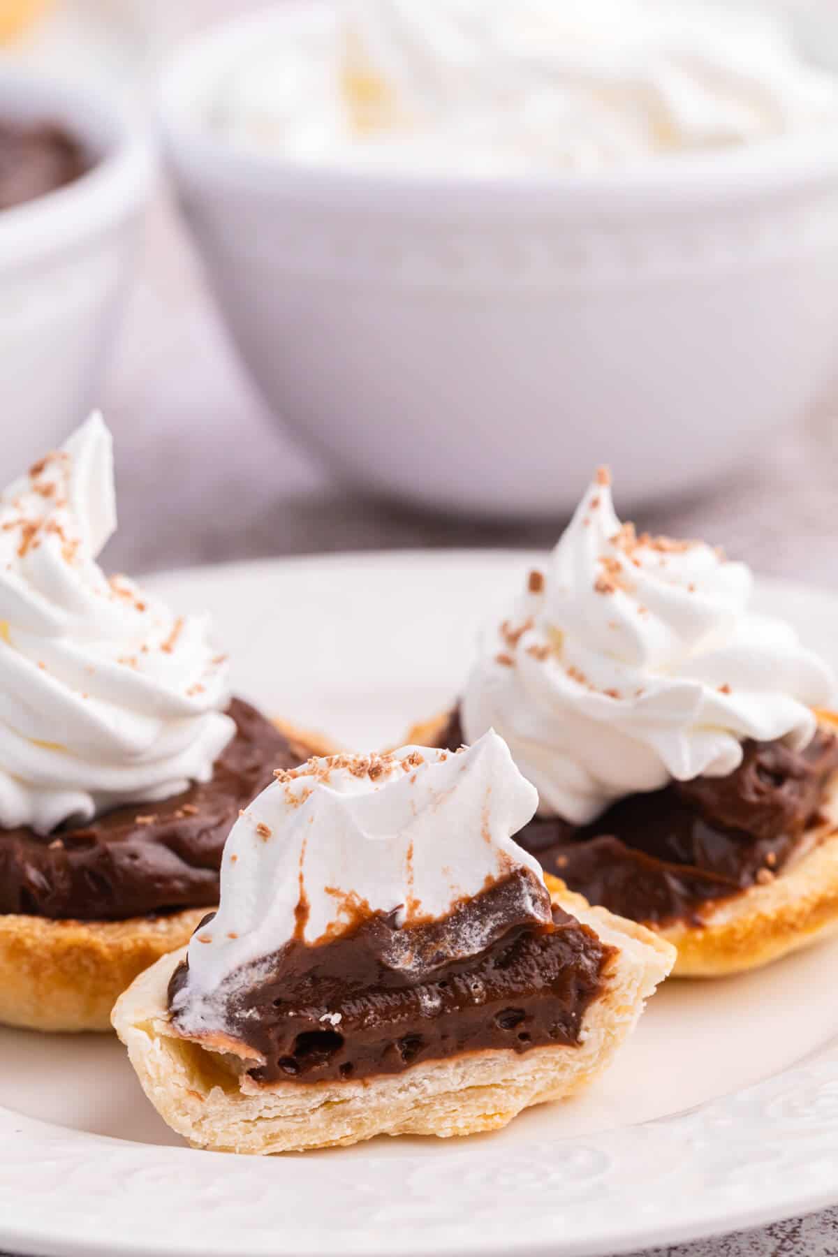 Chocolate cream tarts on a plate with one cut in half.