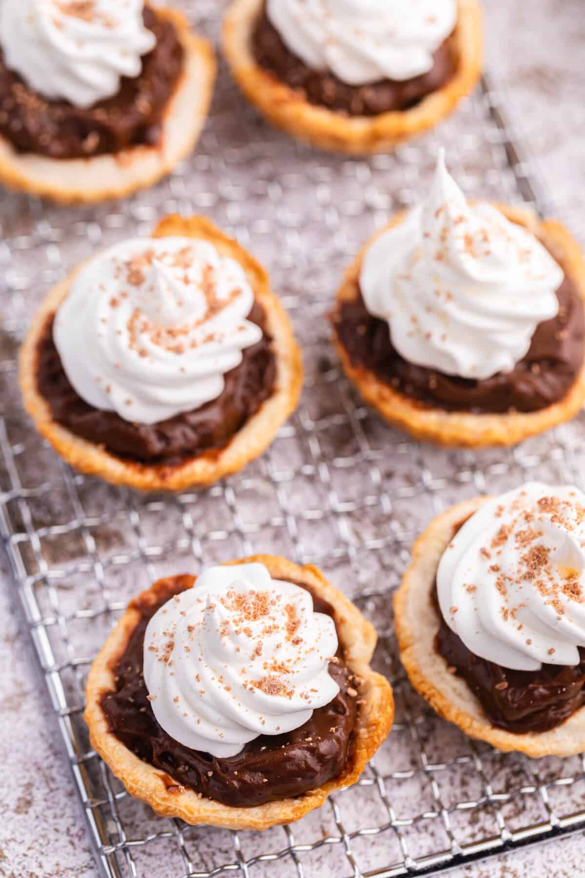 Chocolate cream tarts on a wire rack.