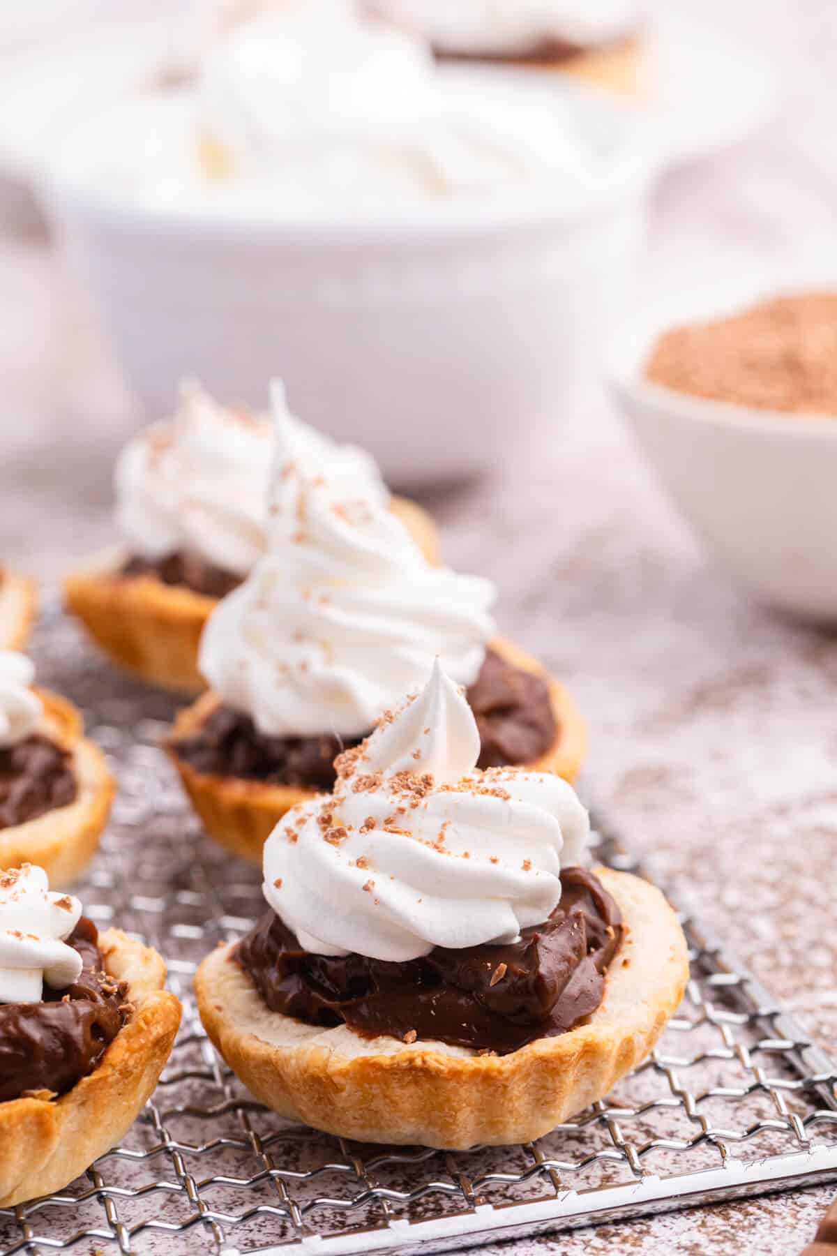 Chocolate cream tarts on a wire rack.