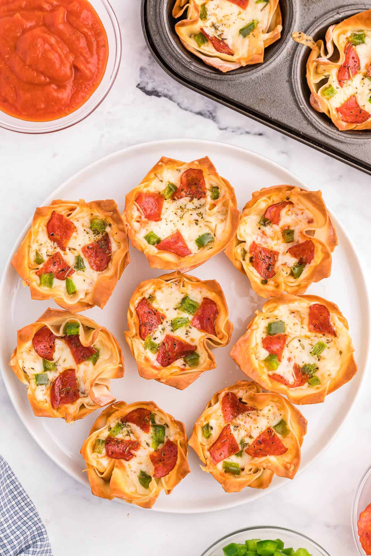 Overhead photo of pizza wonton cups on a white plate.