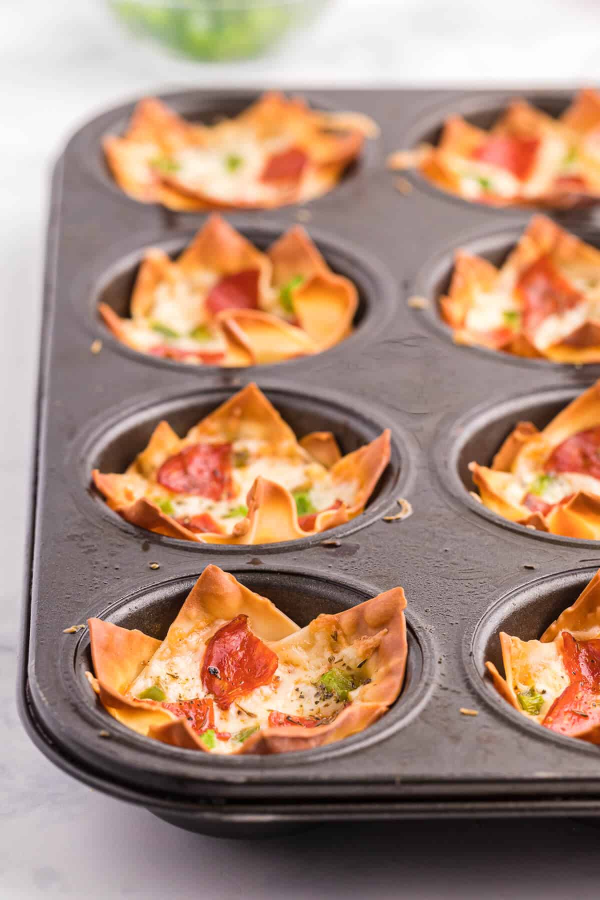 Pizza Wonton Cups Recipe - East meets West in this simple crunchy appetizer. A crispy wonton is filled with cheesy pizza goodness with any toppings you want!