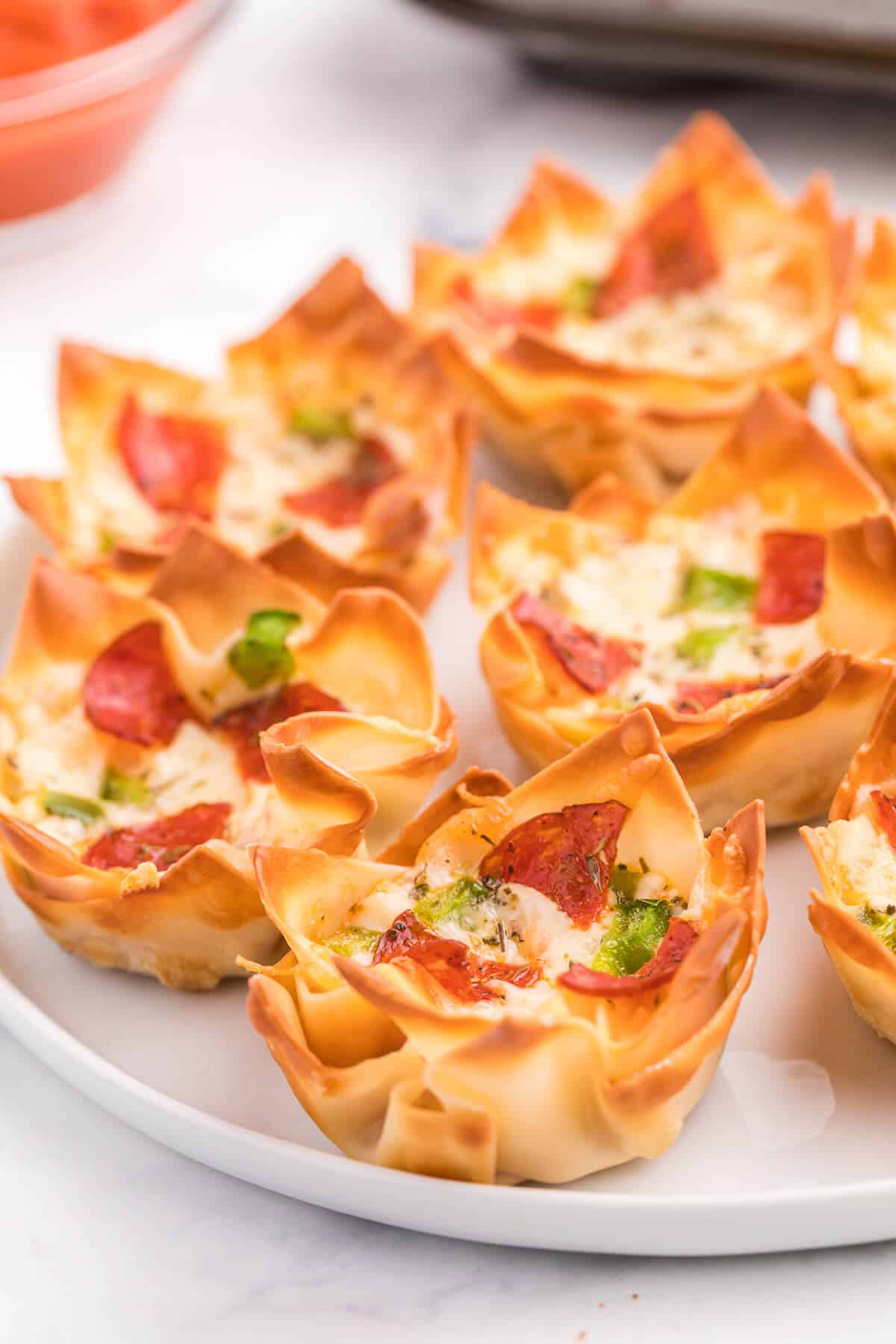 Pizza Wonton Cups Recipe - East meets West in this simple crunchy appetizer. A crispy wonton is filled with cheesy pizza goodness with any toppings you want!