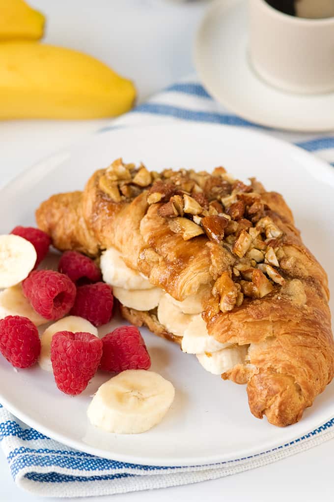 Sticky banana croissant on a plate with fresh fruit.