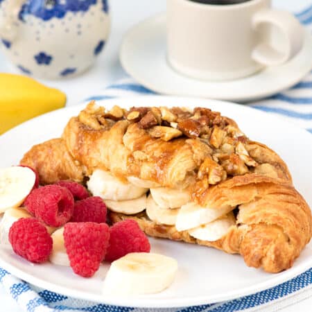 Sticky banana croissant on a plate with fruit.