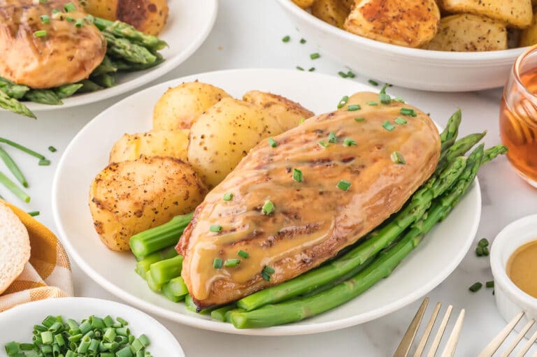 Grilled honey dijon chicken on a plate with asparagus and potatoes.