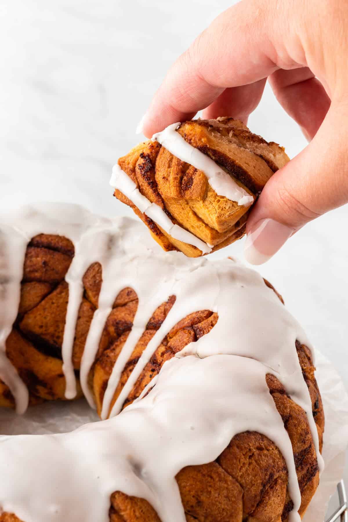 A hand holding a piece of cinnamon roll monkey bread.