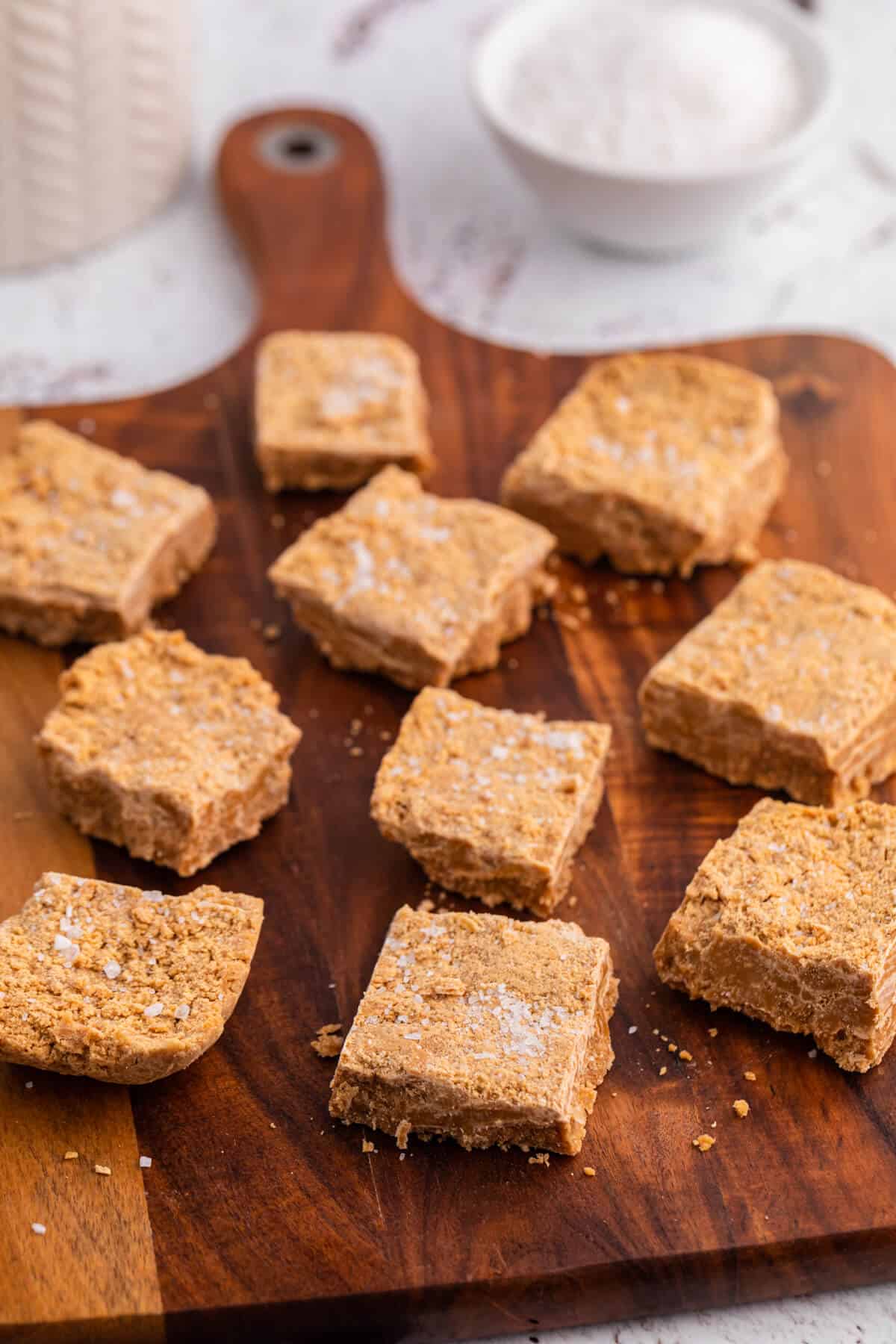 Salted caramel fudge cut into squares on a wooden cutting board.
