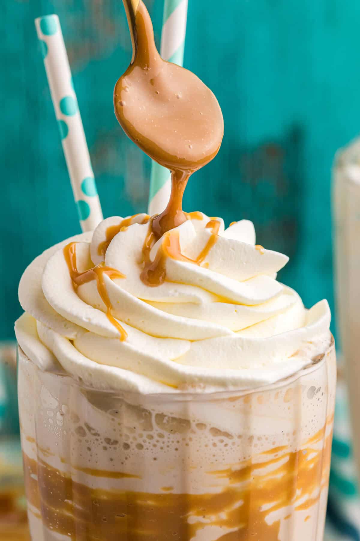 A spoon drizzling dulce de leche on a coffee milkshake.