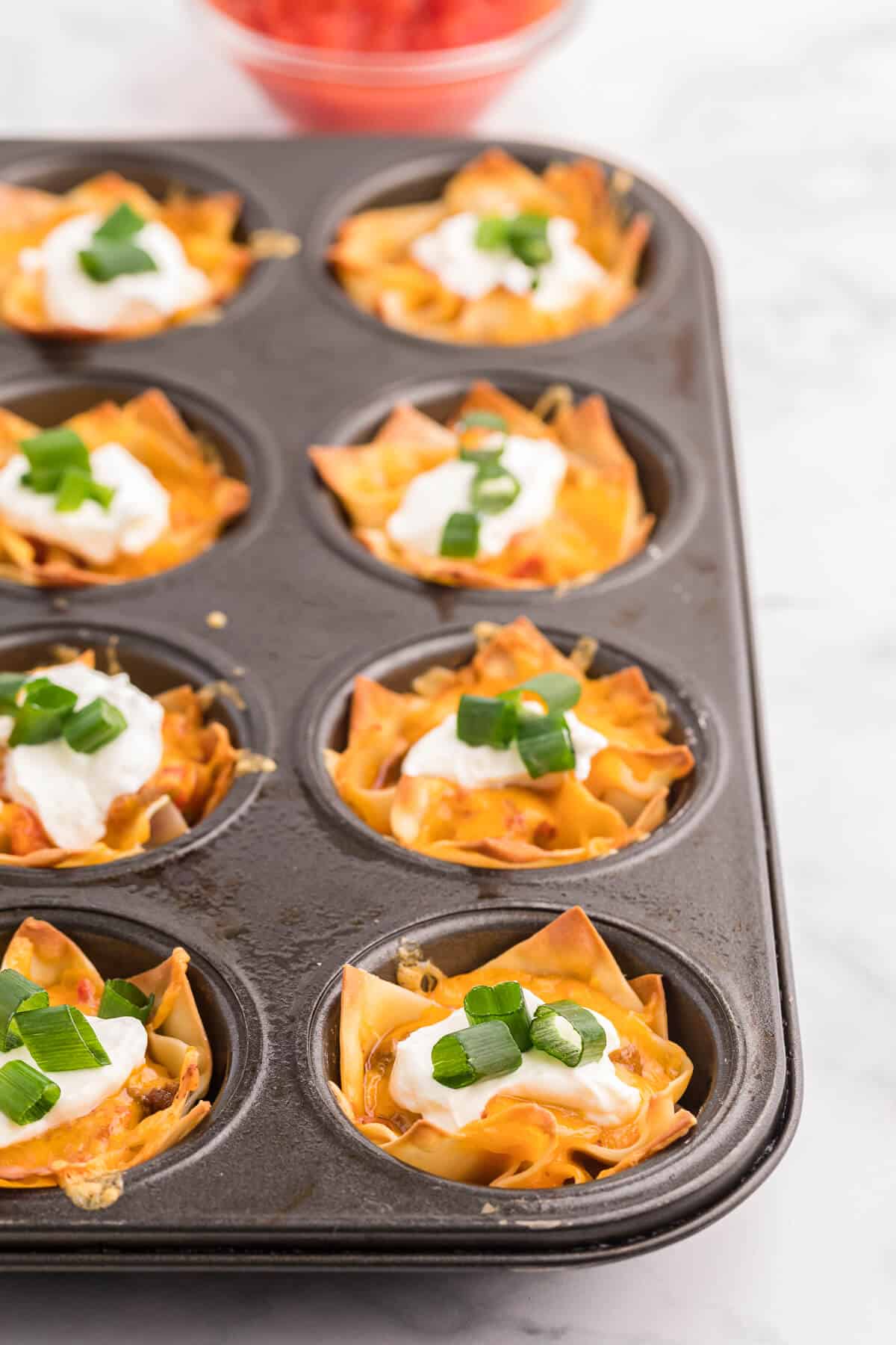 Taco Wonton Cups - Make this yummy appetizer in a muffin tin with wonton wrappers! Top the seasoned taco beef with your favourite fresh toppings and melted cheese and watch these crispy treats disappear in a flash.