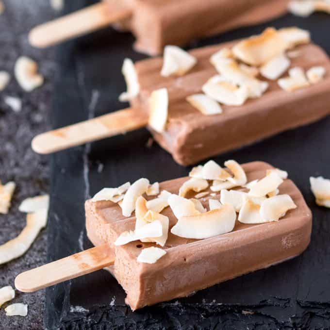 Toasted coconut fudgsicles on a black surface.