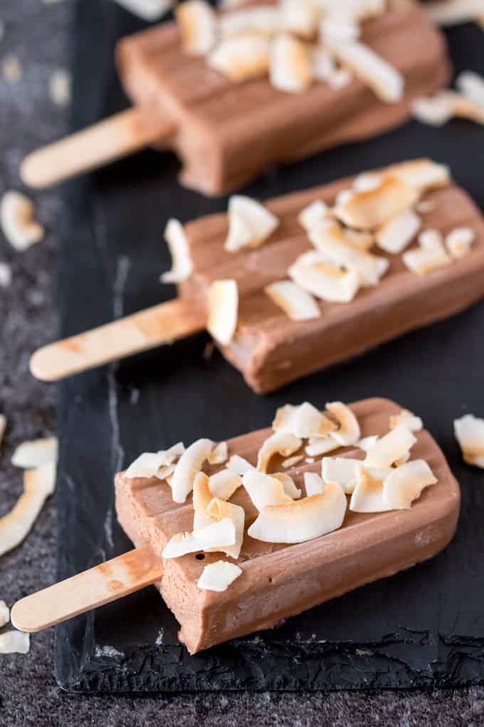 Toasted coconut fudgsicles on a black surface.