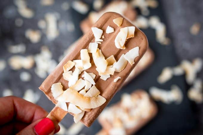 A hand holding a toasted coconut fudgsicle.