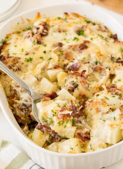 Bacon ranch potatoes in a casserole dish with a serving spoon.